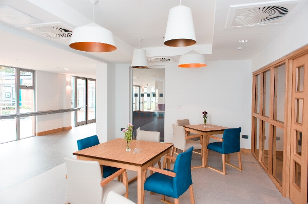 A naturally lit spacious dining area with long windows viewing the courtyard at Kingsley care home